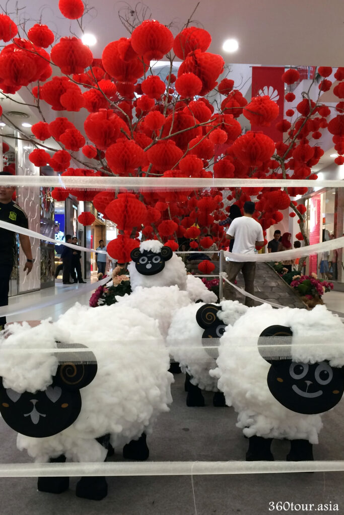 The herd of woolly white Sheeps in front of the Red Lantern tree at the court between Center and West Court of the Spring Mall during Chinese New Year 2015. 