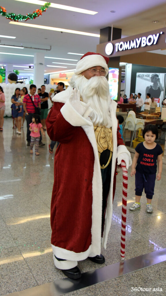 Well costumed Santa Clause walking around the mall wishing children merry Christmas, bringing along small gifts and photographic opportunity