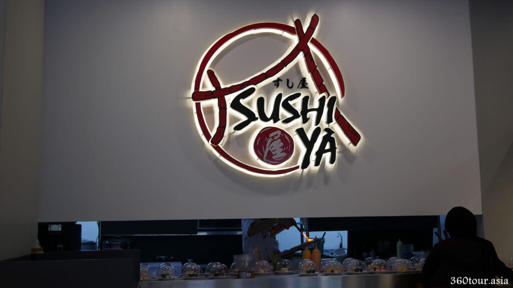 The huge Sushi YA logo lighting at the sushi preparation counter