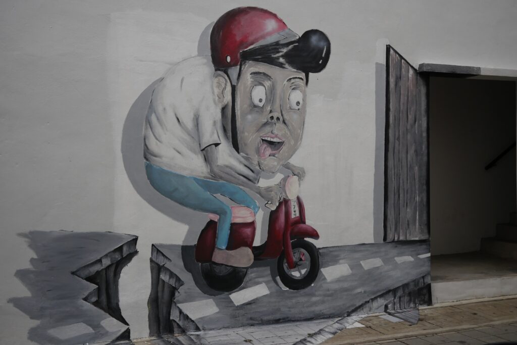 3D壁画描绘了一名摩托车驾驶员在破碎的道路上朝着敞开的门袭击他的踏板车