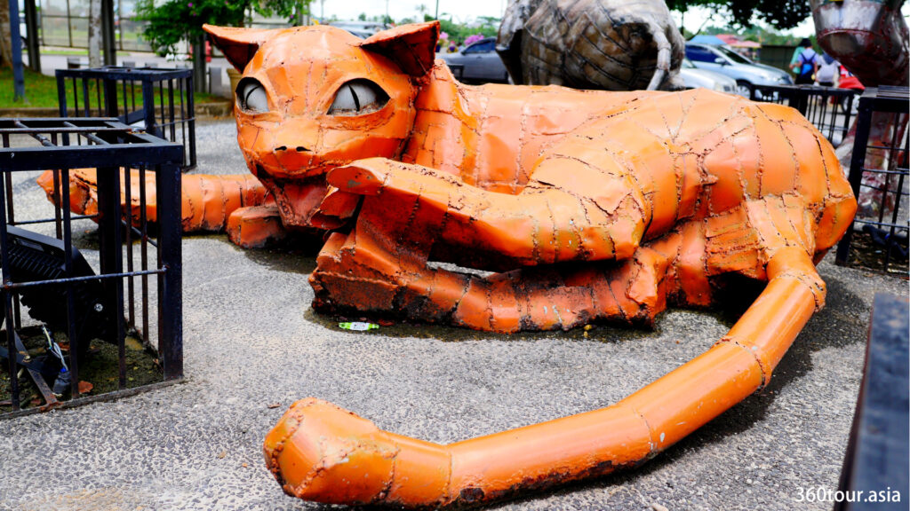 One of the crape metal cat sculpture featuring an orange cat lying down on the ground