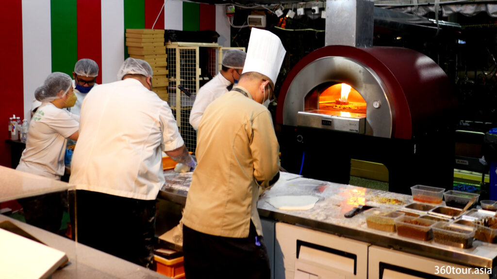 The chef busying preparing the dough in front of a hot oven.