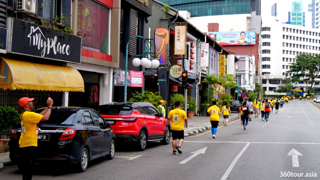 Marathon runners run along the old town of Padungan Road.